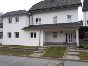 uma casa branca com uma porta da frente e escadas em Ferienwohnung Gashi em Winterberg
