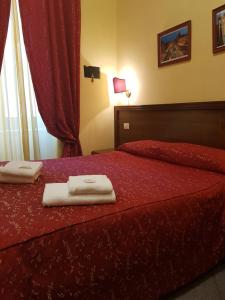 een slaapkamer met een rood bed en handdoeken erop bij B&B Rudy in Rome