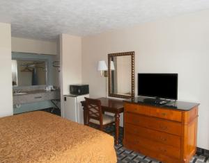 a hotel room with a bed and a dresser with a television at Americas Best Value Inn - Augusta / South in Augusta +13 photos