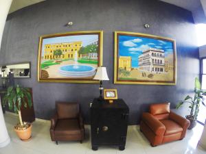 een wachtkamer met twee stoelen en schilderijen aan de muur bij Hotel Oriente in Veracruz
