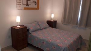 1 dormitorio con 1 cama y 2 mesitas de noche con lámparas en Relax.guarapari en Guarapari