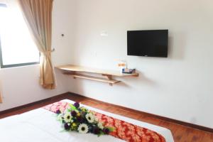 a room with a television and a bed with flowers on it at Am Transit Inn in Kuala Terengganu