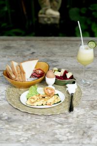 een tafel met een bord eten en een glas sap bij Imagine Bali in Ubud