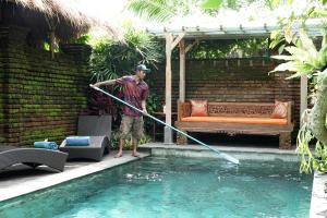 um homem segurando uma mangueira de água ao lado de uma piscina em Imagine Bali em Ubud