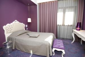 a purple bedroom with a bed and a white desk at Hotel La Pergola in Grezzana