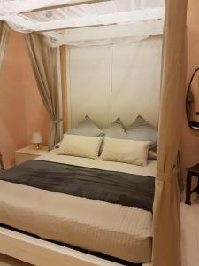 ein Schlafzimmer mit einem Himmelbett mit weißer Bettwäsche und Kissen in der Unterkunft Appartamento Via Matteotti in Sanremo