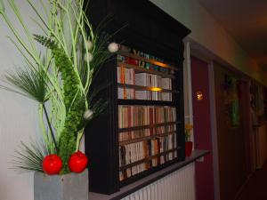 a book shelf filled with books and red tomatoes at Hotel Du Croisé in Marcq-en-Baroeul