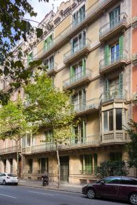 un grand bâtiment avec des voitures garées devant lui dans l'établissement Quartprimera Apartments, à Barcelone