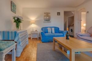 a living room with blue chairs and a table at The Garden Apartment in Teignmouth