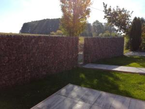 a brick fence in front of a yard with grass at Comfortable house for relax and sports in Hněvkovice