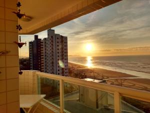 ein Balkon mit Blick auf den Strand bei Sonnenuntergang in der Unterkunft Amor e aconchego beira mar e ar condicionado in Solemar