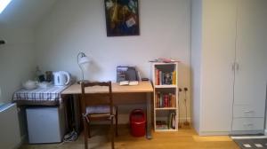 een bureau met een stoel naast een boekenplank bij B&B Wannes Suite in Leuven