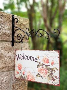 a sign hanging on a stone wall with a welcome sign at Around The Tree Manor in Shitan