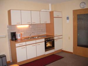 uma cozinha com armários brancos, um lavatório e um forno em Haus Delphin em Neuharlingersiel