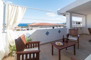 balcone con sedie, tavolo e vista sull'oceano di White Rose Suite Apartment a Cala Gonone