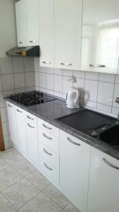 uma cozinha com armários brancos e um balcão preto em Apartments Varos em Split