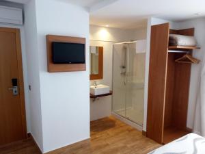 
a bathroom with a sink and a television at Hotel Avenida in Benicàssim
