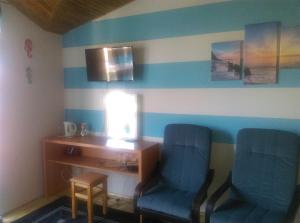 a room with two blue chairs and a desk with a lamp at Pokoje u Jolanty in Władysławowo