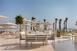 a restaurant with tables and chairs and umbrellas at Herbert Samuel Hod Dead Sea Hotel in Ein Bokek