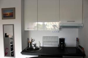 a kitchen with a sink and white cabinets at Studio 237 Port Camargue, Piscine, Climatisation, 2 personnes in Le Grau-du-Roi