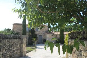 una casa de piedra con un muro de piedra y un árbol en Mas Oréa côté piscine, en Gordes