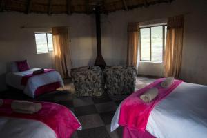 Sani Stone Lodge في Mokhotlong: غرفة نوم بسريرين وملاءات وردية ونوافذ