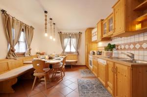 a kitchen with wooden cabinets and a table with chairs at Chaletapartement Ambiente Villa Mozart in Chienes