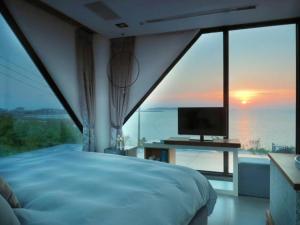 a bedroom with a large window with a bed and a television at Villa Iris in Baisha