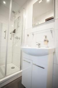 a white bathroom with a sink and a shower at Waldheim in Nürtingen