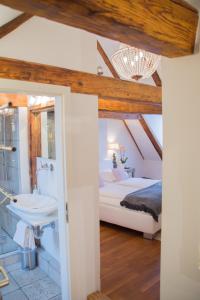 a bedroom with a bed and a bathroom with a sink at L'Ostello Altstadthotel in Regensburg