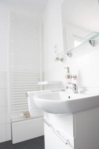 a white bathroom with a sink and a mirror at Waldheim in Nürtingen