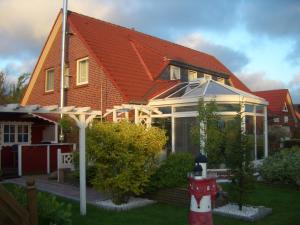 uma casa com um telhado vermelho e um hidrante vermelho em Haus Delphin em Neuharlingersiel