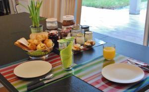 a table with plates of food and glasses of orange juice at Villa Donosti Chambres d'Hôtes in Lanton