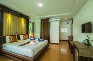 a bedroom with a large bed and a television at Lanta Nice Beach Resort - SHA Extra Plus in Ko Lanta