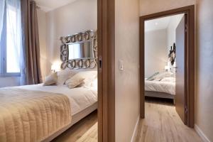 1 dormitorio con 1 cama grande y espejo en Residence du Louvre - LRA Cannes, en Cannes