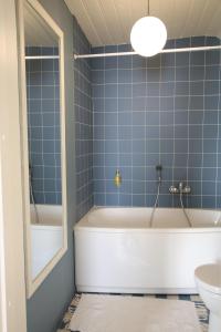a blue tiled bathroom with a tub and a toilet at Meke in Mustkalni