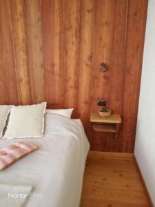 um quarto com uma cama branca e uma parede de madeira em Agriturismo Au Jardin Fleuri em Antey-Saint-André