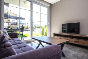 a living room with a couch and a tv and a table at Lara Beach Homes in Lara