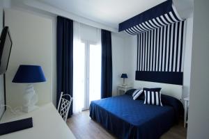 a bedroom with a blue bed and a large window at Hotel Nautilus in Cagliari