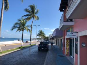 Hostel Tropico 20º في كوزوميل: a car driving down a street next to the beach
