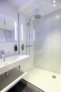 baño blanco con ducha y lavamanos en Hôtel Anne De Bretagne, en Rennes