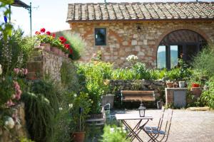 a garden with a table and a bench and flowers at Ancora del Chianti in Greve in Chianti
