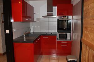 a red kitchen with a sink and a microwave at Chalet Fleur des Alpes in Les Gets