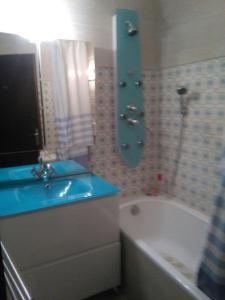 uma casa de banho com um lavatório azul e uma banheira em Sombang em Ferney-Voltaire