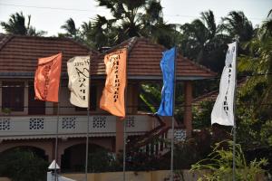 three flags in front of a building with palm trees at Hotel Agape in Mannar