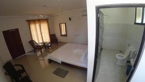 a bedroom with a bed and a toilet in a room at Dolphin Cottage Mirissa in Mirissa