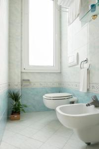 a bathroom with a toilet and a sink and a window at Hotel Kadett in Rimini