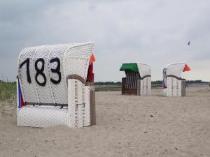una fila de cabañas de playa en una playa de arena en Strandkorb, en Horumersiel