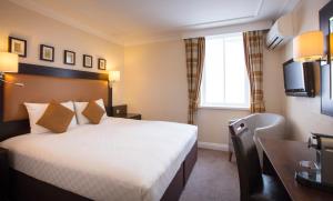 um quarto de hotel com uma cama e uma secretária em Thistle London Heathrow Terminal 5 em Hillingdon