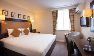 una camera d'albergo con letto e scrivania di Thistle London Heathrow Terminal 5 a Hillingdon